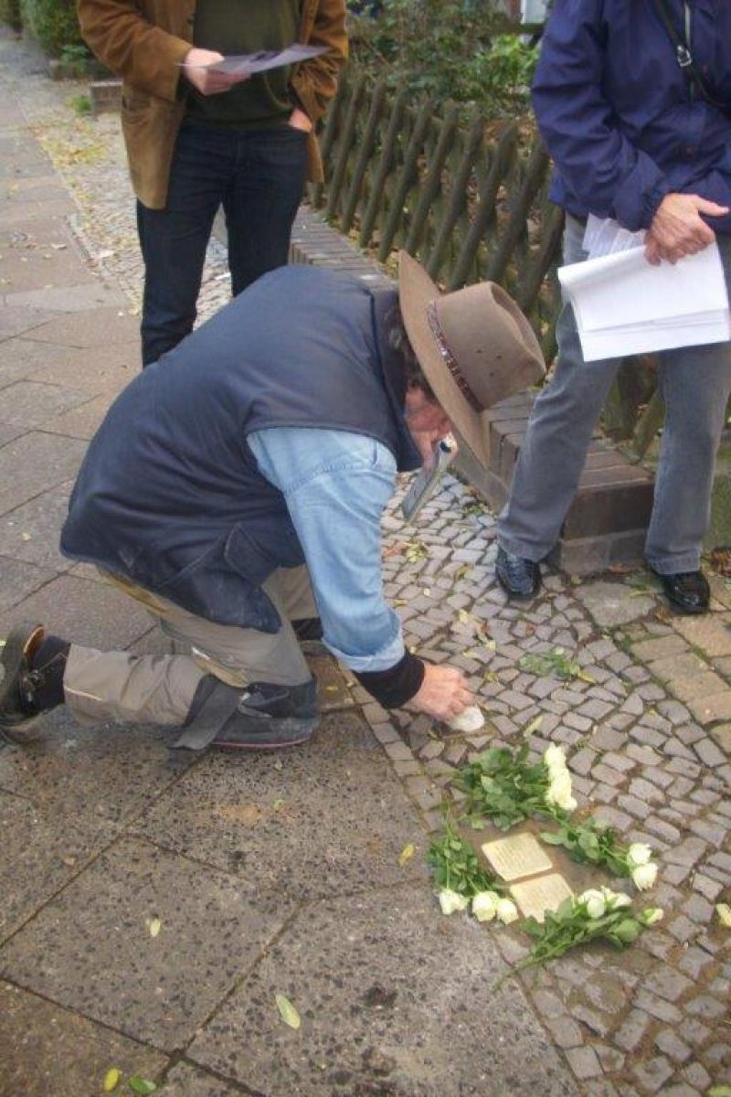 Gunter Demnig reinigt den früher verlegten Stein